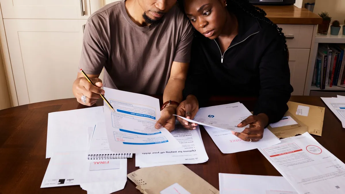 A couple sitting at a kitchen table while reviewing household bills